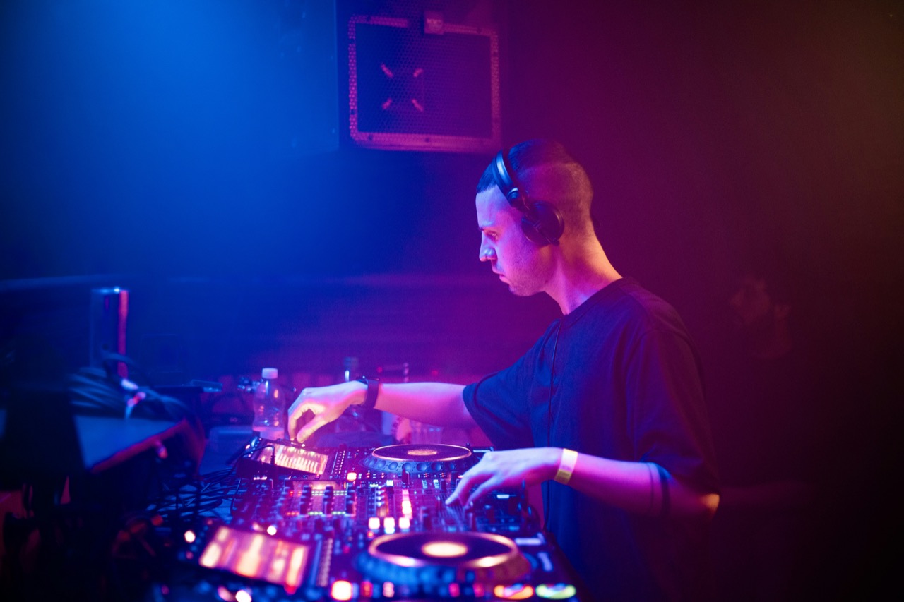 A DJ with headphones searching for the key of the next track.